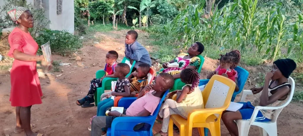 A teacher sharing a Bible lesson with children in a garden