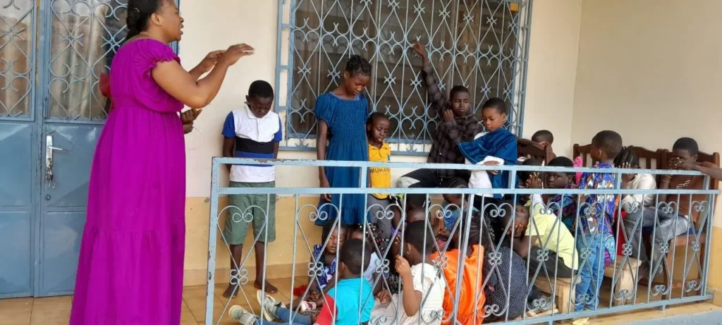 A teacher leading worship with children on a porch