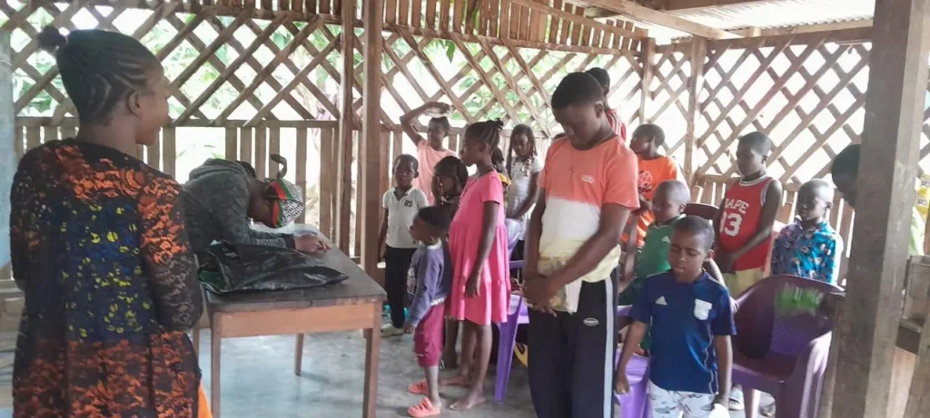 Children standing in prayer in an open-air shelter