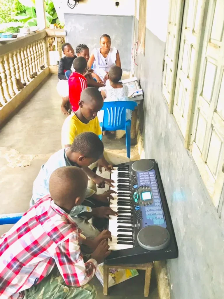 Children learning to play the keyboard on a veranda